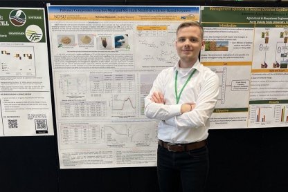 NDSU graduate student standing next to poster board of his work